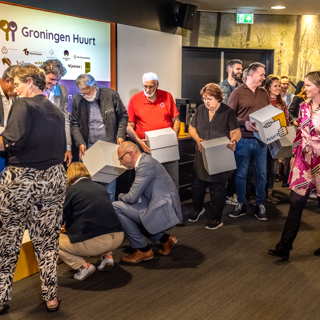 Bestuurders, vertegenwoordigers van de huurdersorganisaties en WoningNet leggen samen de puzzel van het logo van Groningen Huurt.